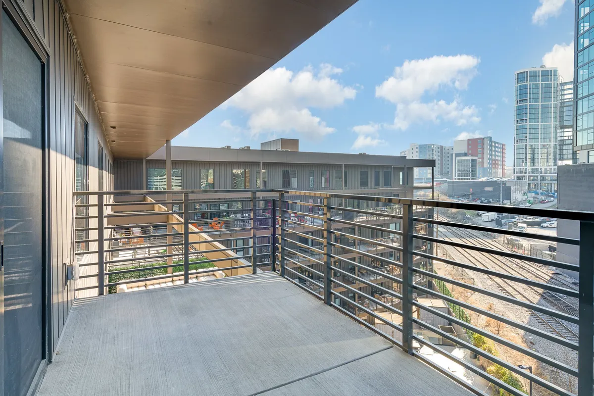 A private balcony with a contemporary railing, offering city views and a peaceful spot for quiet moments. The simple setup provides a sense of escape and exclusive outdoor space directly accessible from the interior.