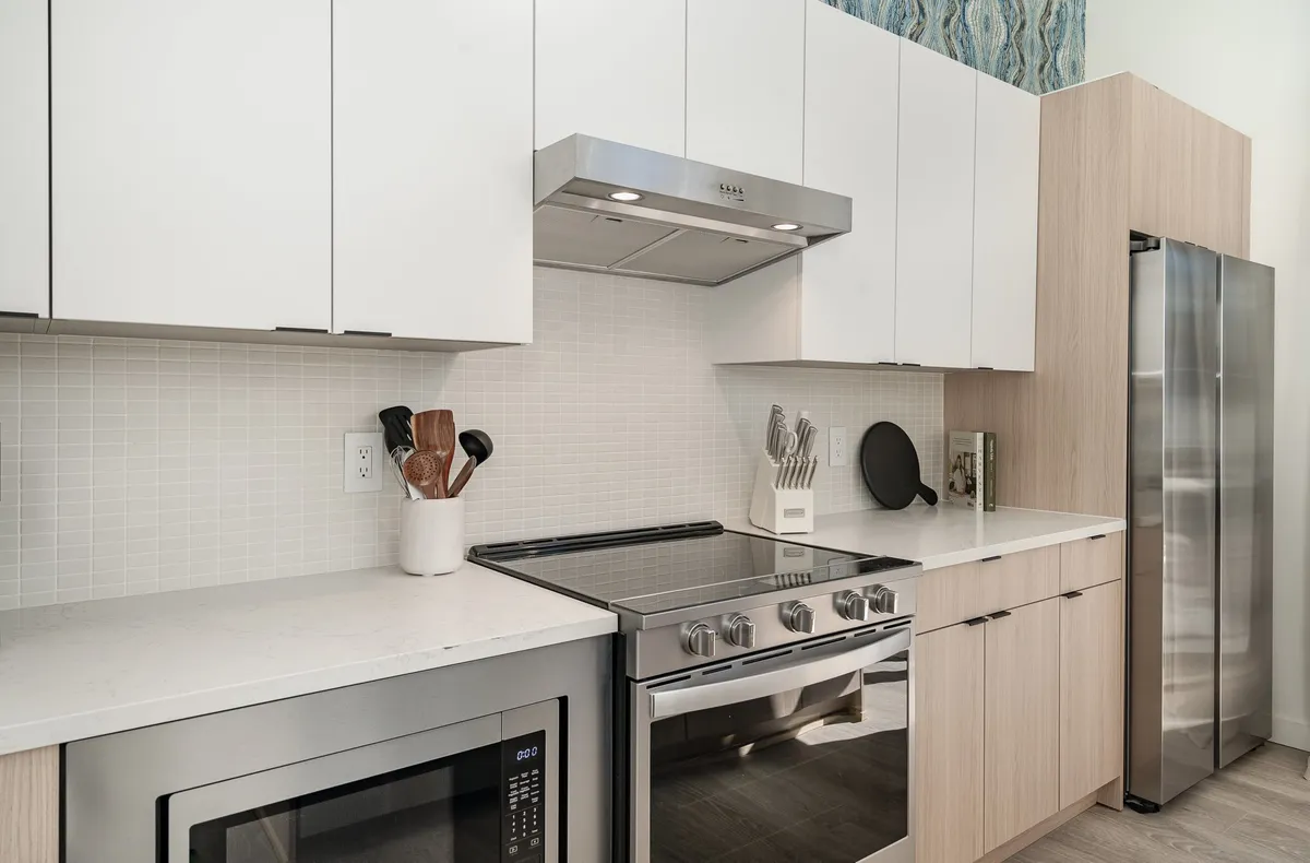 A bright, contemporary kitchen showcasing stainless steel appliances, white cabinetry, and light-colored countertops—offering a clean and functional environment ideal for preparing meals or entertaining.