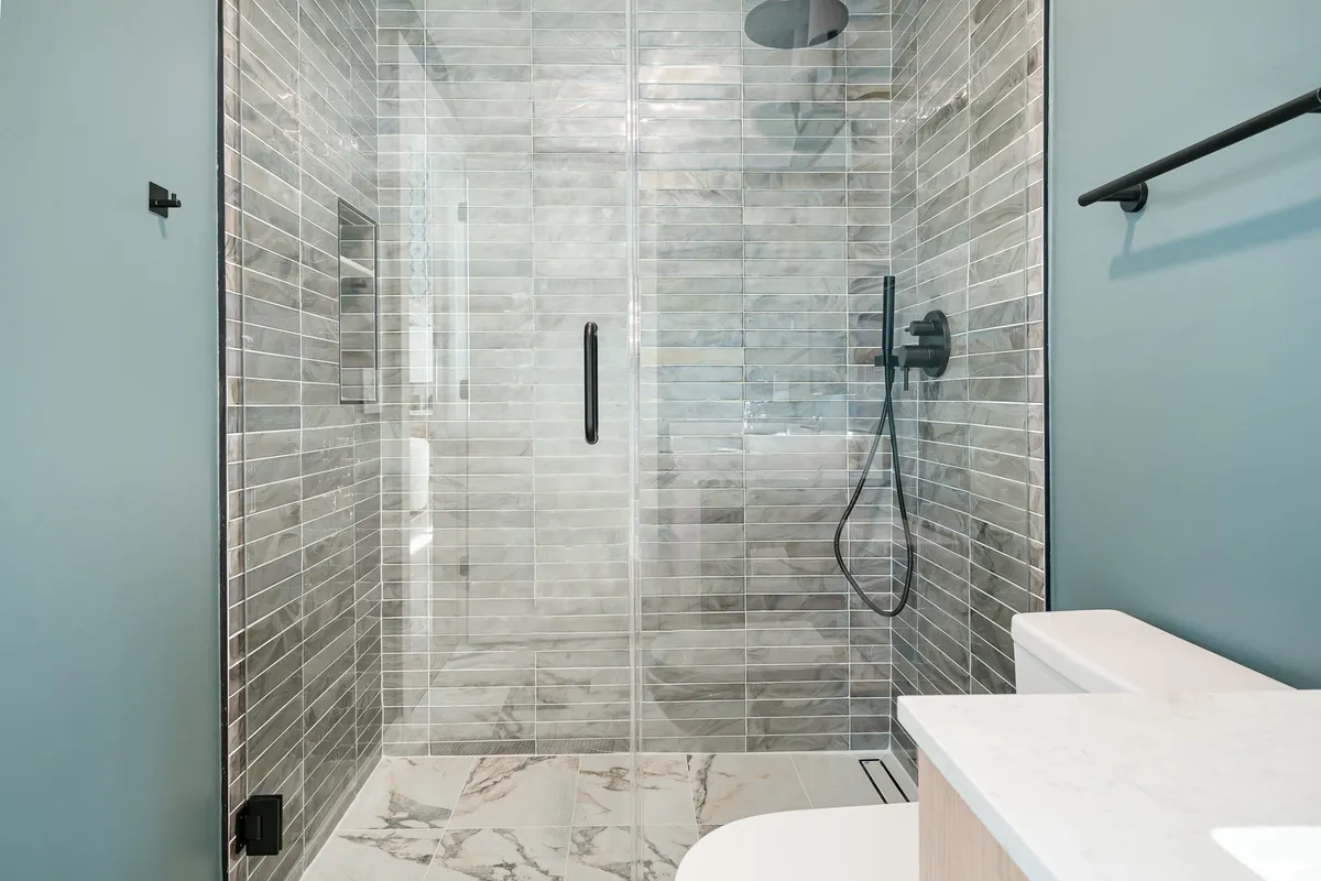 A modern bathroom with a glass-enclosed walk-in shower, sleek fixtures, and marble flooring. The overall mood is tranquil and spa-like, evoking a sense of luxury and rejuvenation.